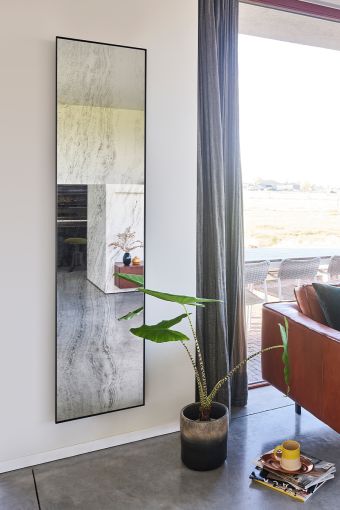 Travertin rectangular wall mirror styled in an interior, highlighting black metal frame.